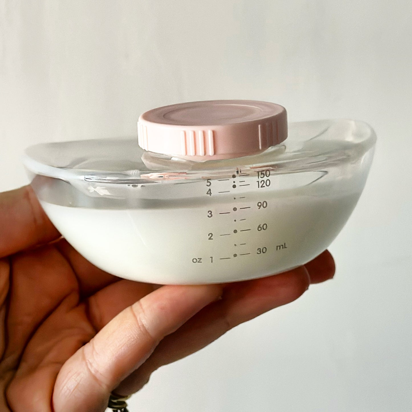 Mum holding the Elevate collection container after she has pumped her milk and put the lid on ready for storage