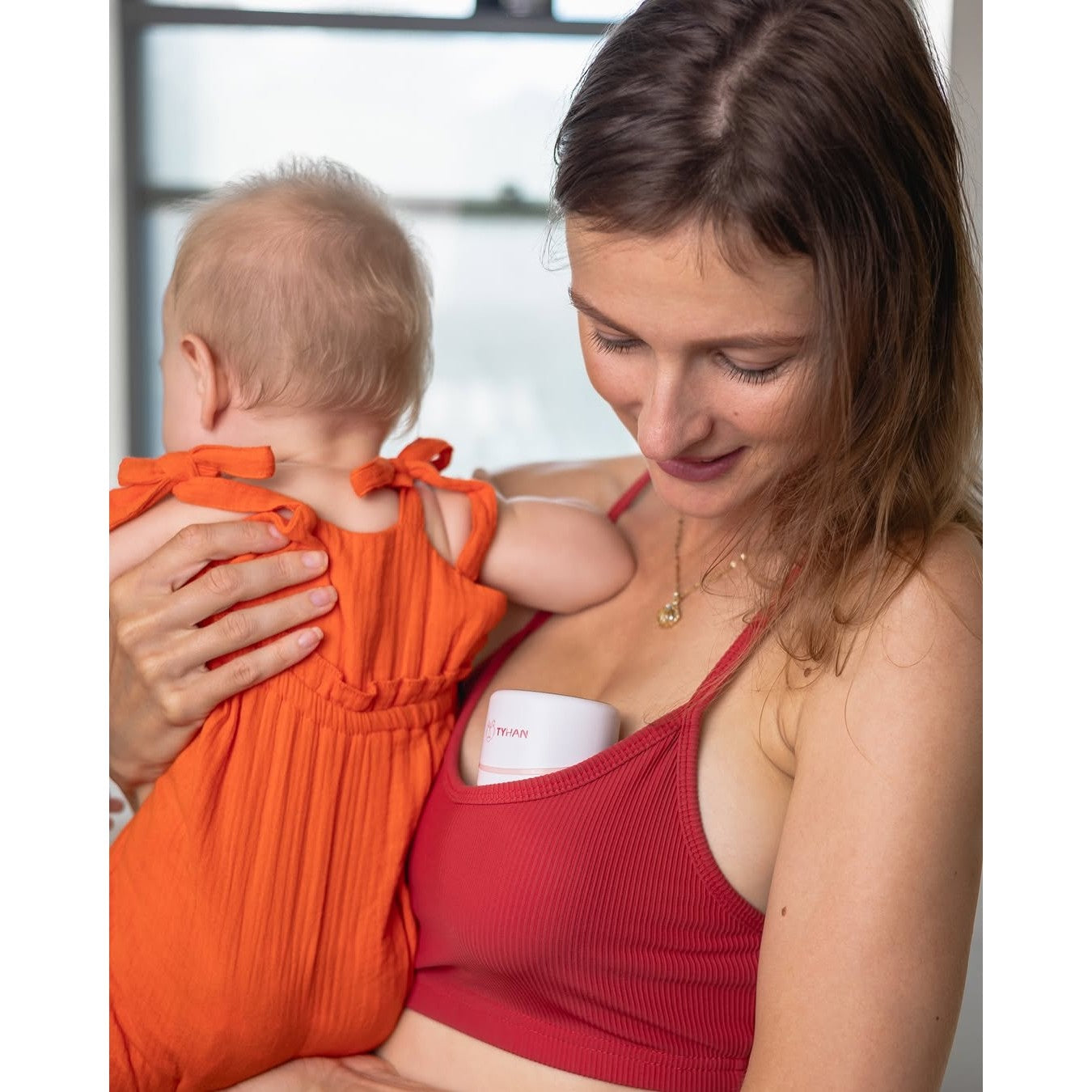 Mum holding her baby while wearing her Tyhan S12 Pro breast pump