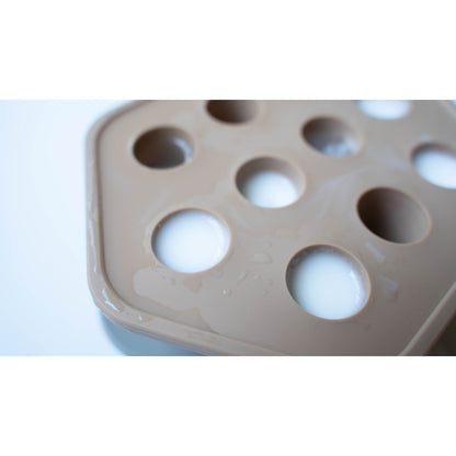 Beige silicone mold with multiple round cavities on a white background