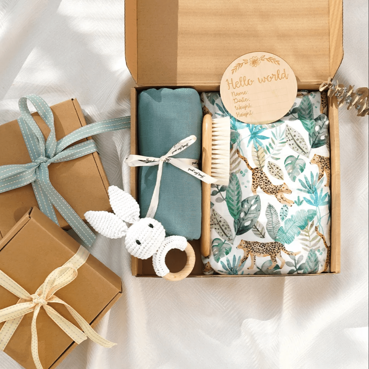 Image of baby shower gift box with two blankets and muslin wraps with brush, rattle and newborn plaque