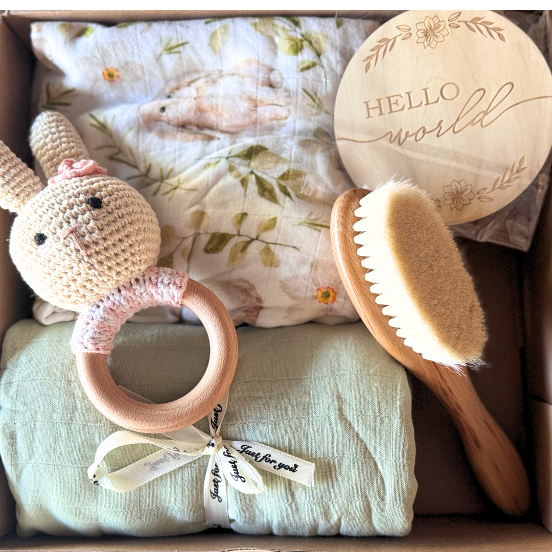 Image of baby shower gift box with two blankets and muslin wraps with brush, rattle and newborn plaque