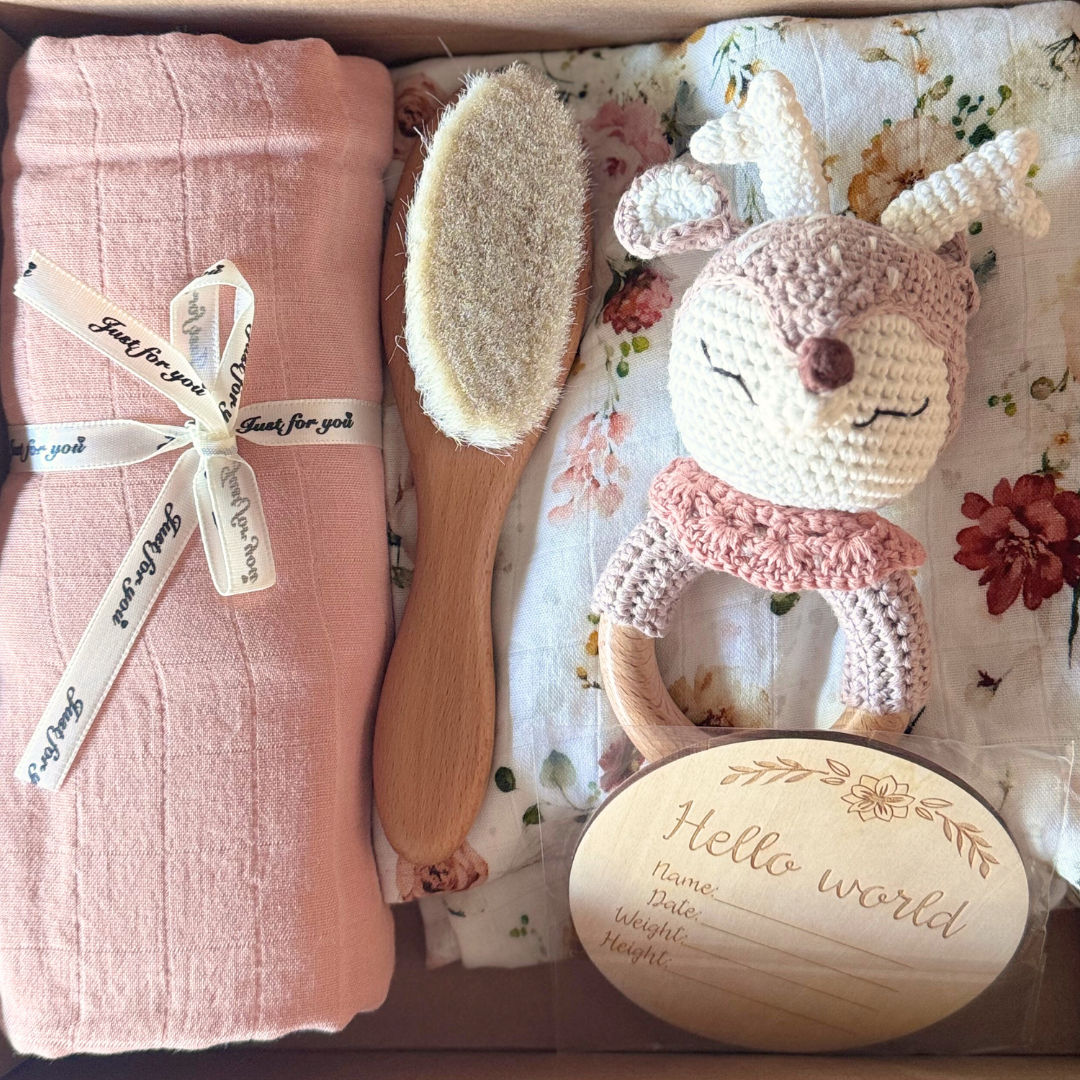 Image of baby shower gift box with two blankets and muslin wraps with brush, rattle and newborn plaque