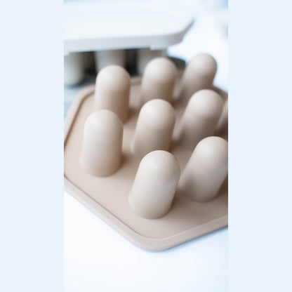 Beige silicone ice cube tray with multiple compartments on a white background